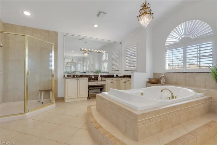 Bathroom featuring vanity, a chandelier, a shower stall, a bath, and recessed lighting
