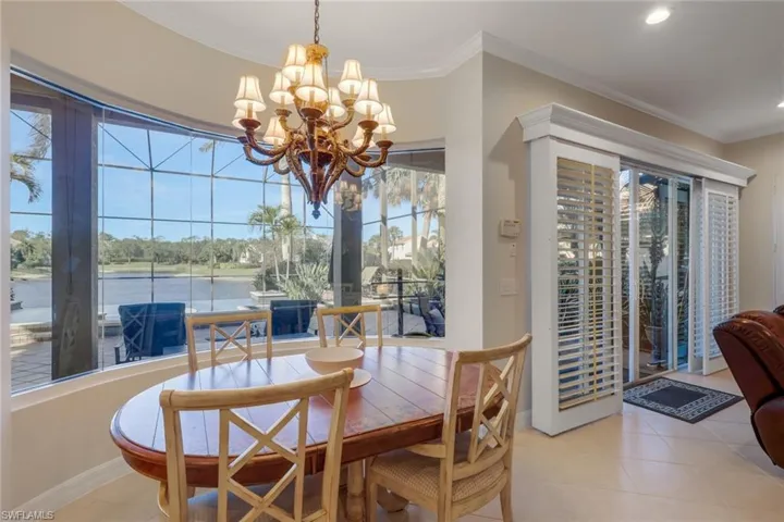 Dining room with ornamental molding, a chandelier, light tile patterned floors, and a water view