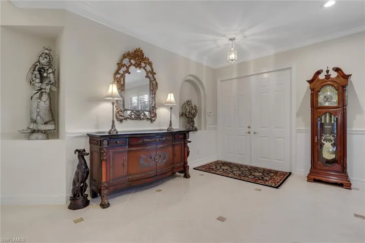 Entrance foyer with ornamental molding, wainscoting, and tile patterned floors