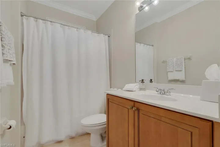 Full bath with ornamental molding, a shower with curtain, vanity, and light tile patterned flooring