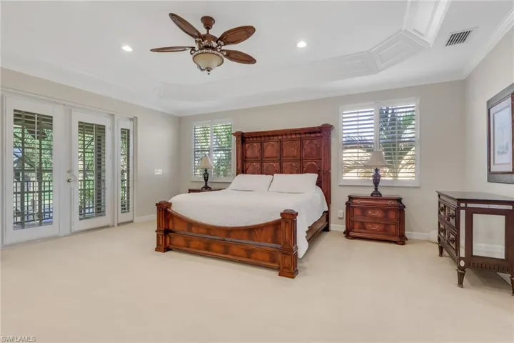 Bedroom featuring light colored carpet, access to outside, crown molding, multiple windows, and ceiling fan