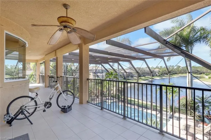 View of patio featuring a ceiling fan, a lanai, an outdoor pool, and a water view