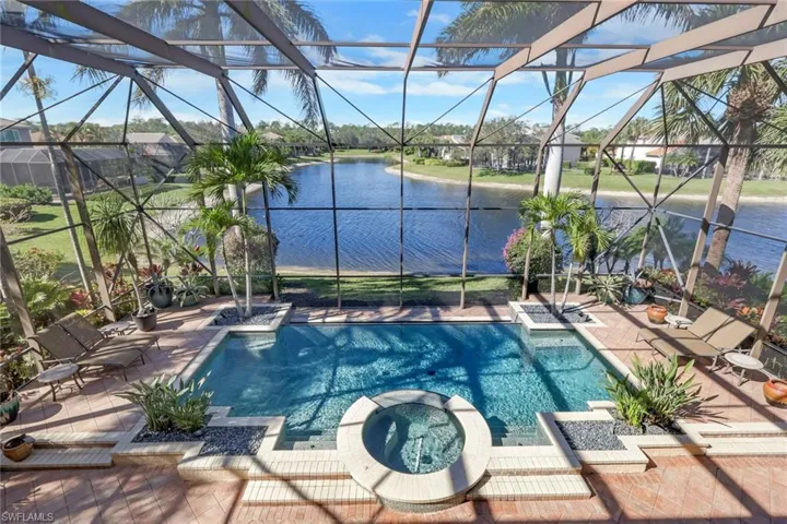 View of pool featuring a sunroom, a pool with connected hot tub, a water view, a lanai, and a patio area