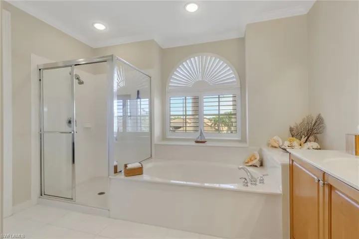 Full bath featuring vanity, a bath, a shower stall, crown molding, and light tile patterned flooring