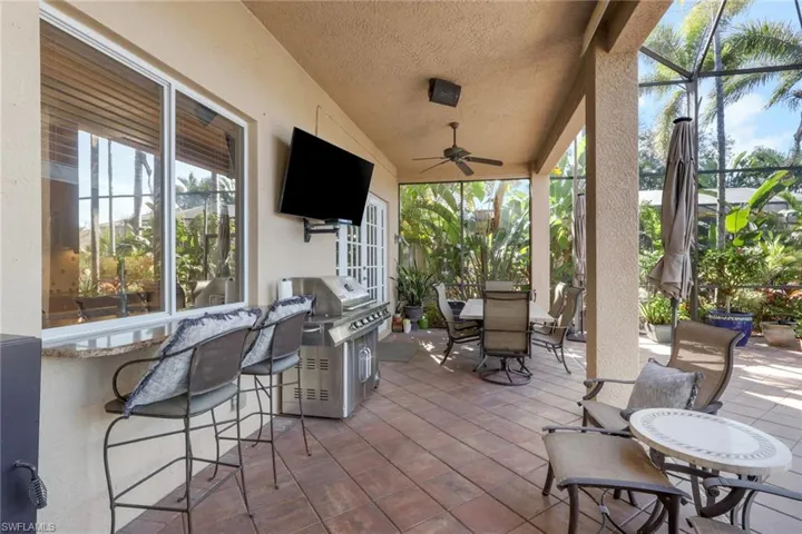View of patio with outdoor dining space, a ceiling fan, a lanai, a sunroom, and an outdoor kitchen