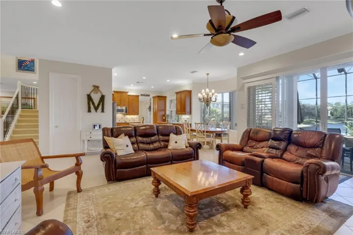 Living room with stairway, a chandelier, ceiling fan, light tile patterned floors, and recessed lighting