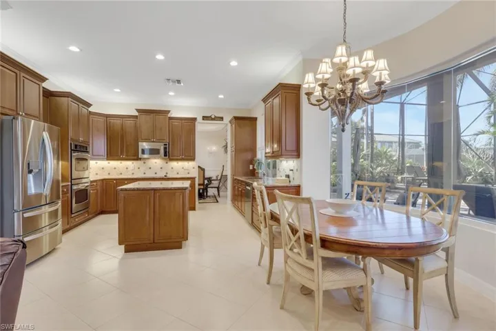 Kitchen featuring stainless steel appliances, brown cabinets, decorative backsplash, hanging light fixtures, and a center island