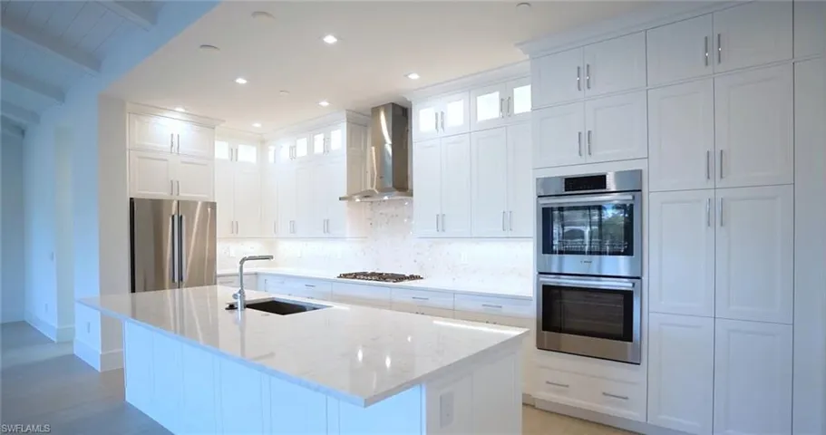 Kitchen with stainless steel appliances, light hardwood / wood-style flooring, wall chimney exhaust hood, tasteful backsplash, and sink