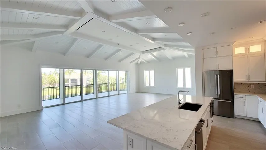 Expansive living room featuring lofted ceiling with beams and shiplap wood