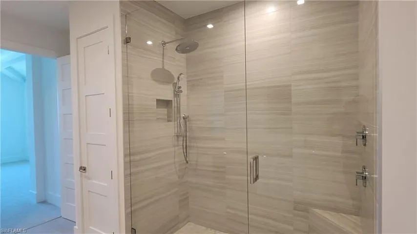 Bathroom featuring an enclosed shower with built in seat and    two shower heads