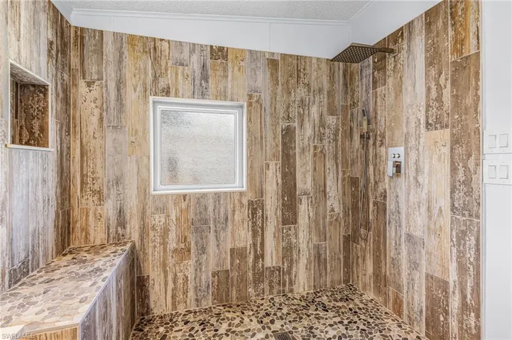 Bathroom with tiled shower and a textured ceiling