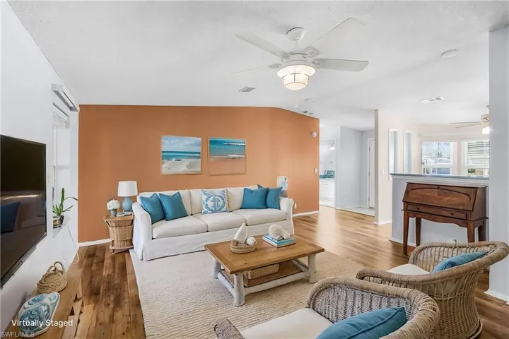 Living room with a ceiling fan, wood finished floors, and vaulted ceiling