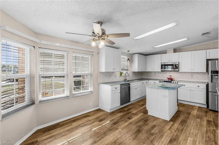 Kitchen featuring a center island, ceiling fan, white cabinetry, and light countertops