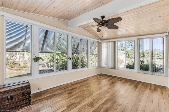 Unfurnished sunroom with vaulted ceiling with beams, wood ceiling, and wood finished floors
