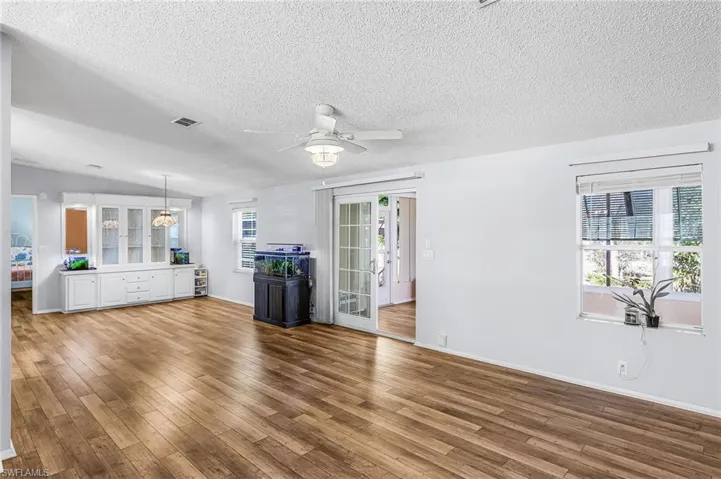 Unfurnished living room featuring a ceiling fan, wood finished floors, and a textured ceiling