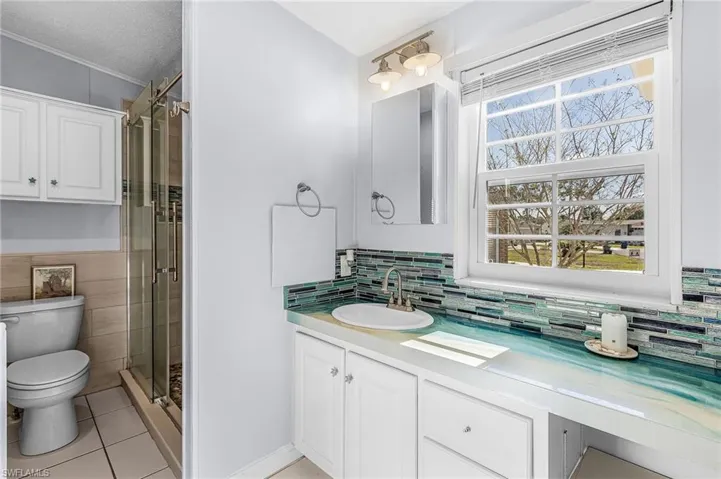 Bathroom with vanity, a stall shower, a textured ceiling, and light tile patterned floors