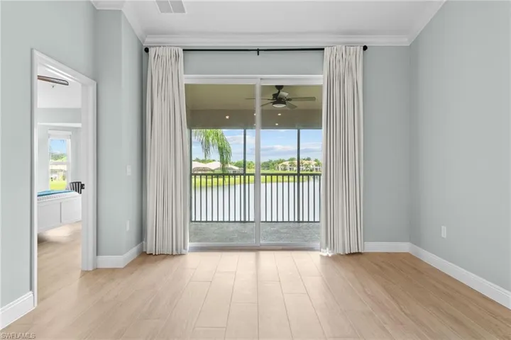 Hurricane impact sliding glass doors open to the screened lanai. View of long part of lake. New window coverings added for privacy and energy efficiency. Lanai is covered/protected with a ceiling fan.