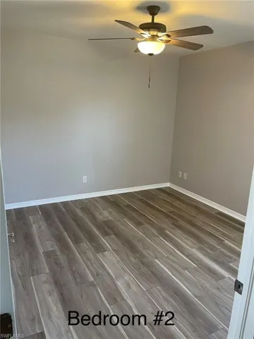 Unfurnished room with ceiling fan and light wood-style laminate flooring.