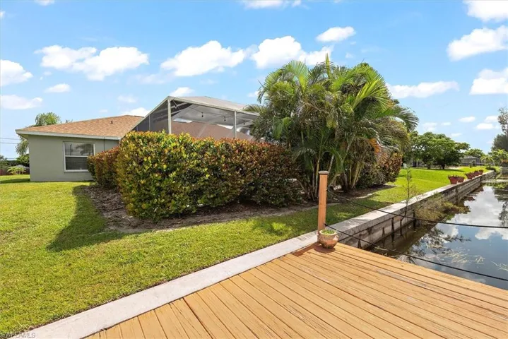 Dock area with a water view, a yard, and glass enclosure