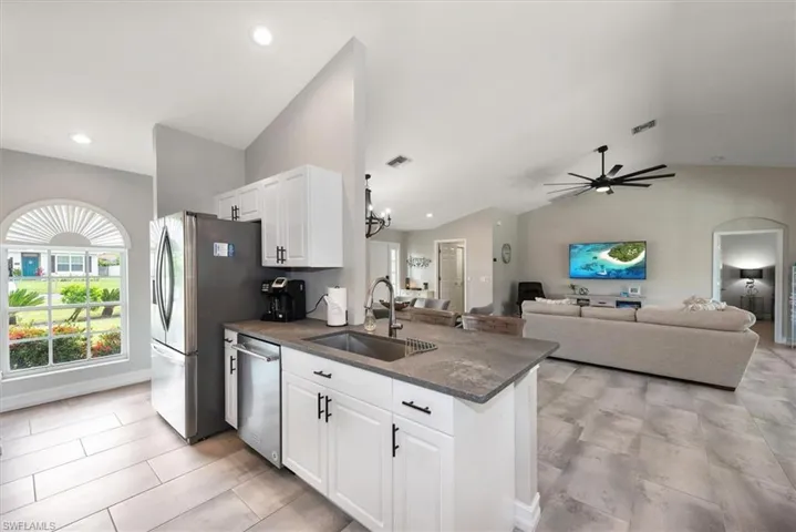 Kitchen with lofted ceiling, stainless steel appliances, white cabinetry, a peninsula, and ceiling fan
