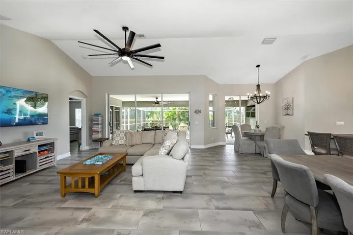 Living room with a chandelier, ceiling fan, and high vaulted ceiling