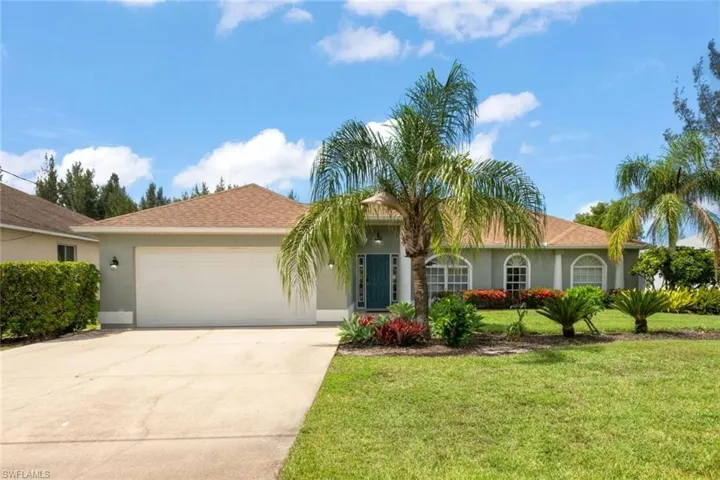 View of front of property featuring stucco siding, driveway, a garage, and a front lawn