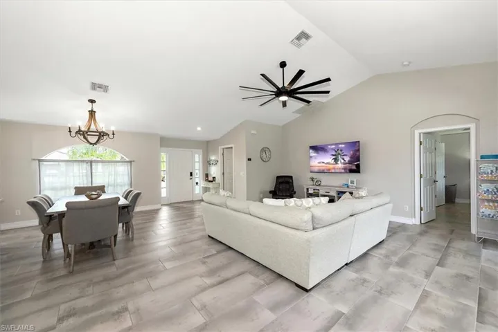 Living room featuring lofted ceiling, a chandelier, and ceiling fan