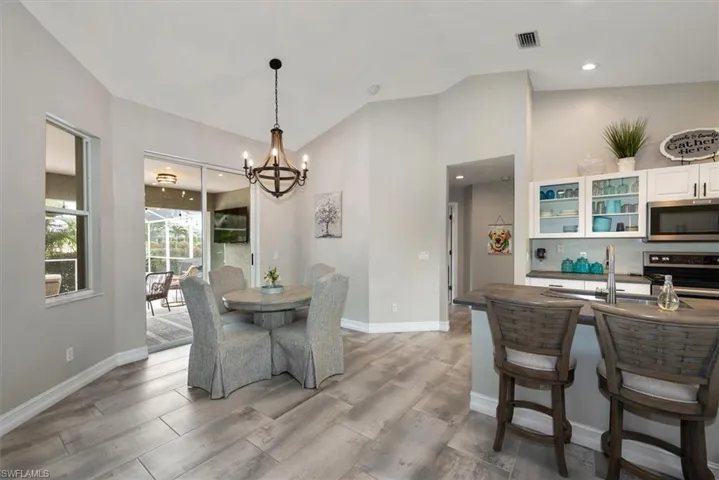 Dining room with a chandelier, light wood-style flooring, vaulted ceiling, and recessed lighting