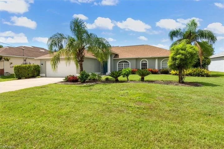 View of front of property featuring driveway, a garage, a front yard, and stucco siding