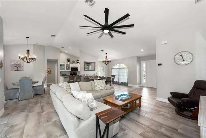 Living room featuring a chandelier, lofted ceiling, recessed lighting, ceiling fan, and light wood-style flooring