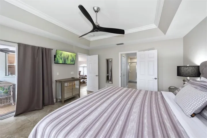 Bedroom featuring ornamental molding, a tray ceiling, and a ceiling fan