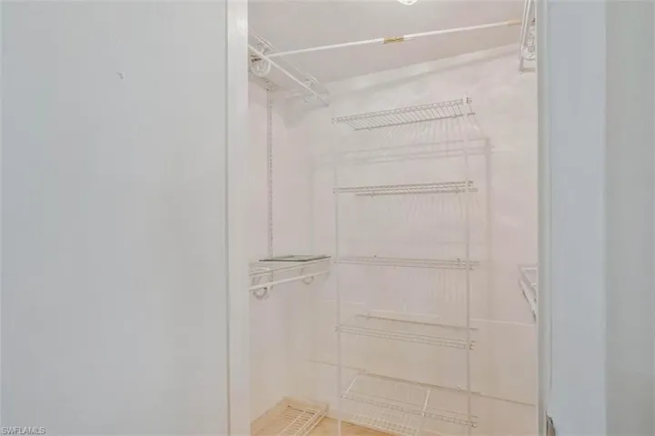 Walk in closet Built-in  shelving system, integrated wire hanging rods, and light-toned wall finishes