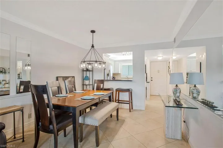 Crown molding, tile flooring, contemporary chandelier, kitchen pass-through, and mirrored wall accents