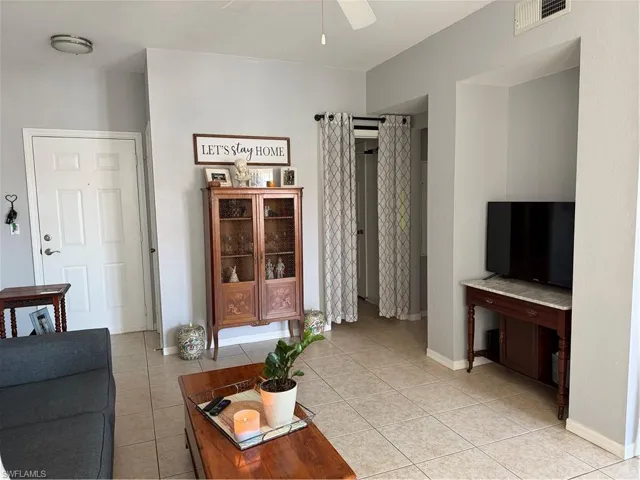 Living area with a ceiling fan and light tile patterned flooring