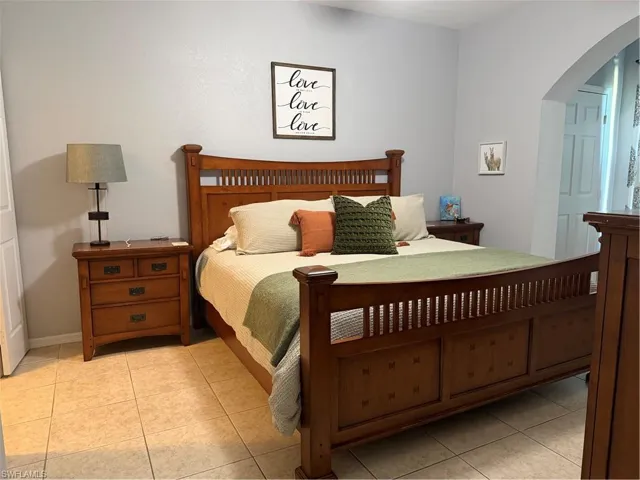 Bedroom with arched walkways and light tile patterned floors