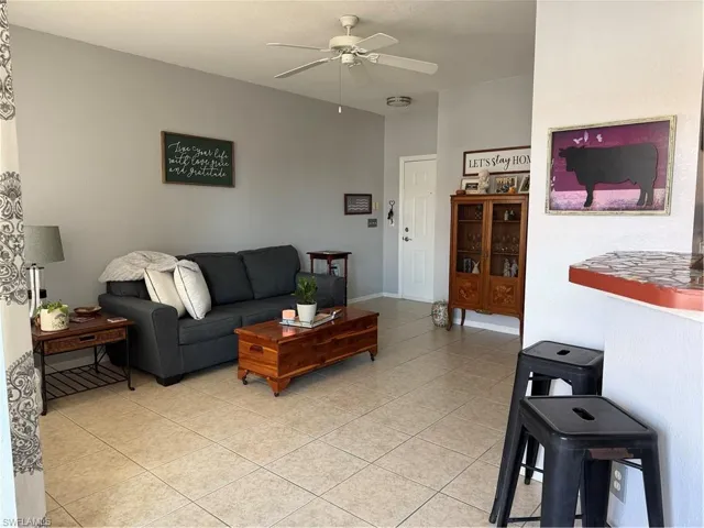 Living area featuring a ceiling fan and light tile patterned flooring