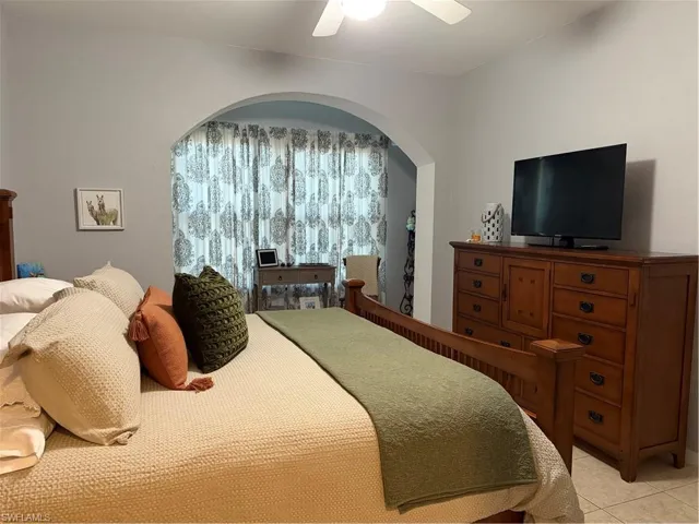 Tiled bedroom featuring arched walkways and a ceiling fan