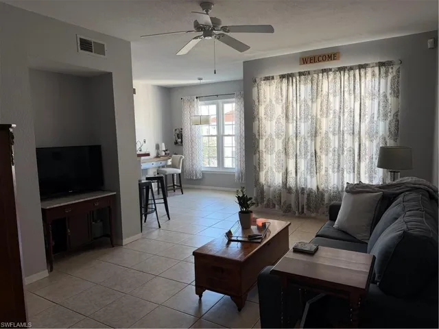 Living area with light tile patterned flooring, ceiling fan, and a textured ceiling