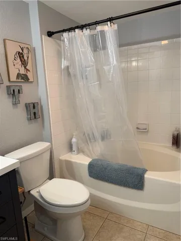 Bathroom with a textured wall, shower / tub combo, vanity, and light tile patterned flooring