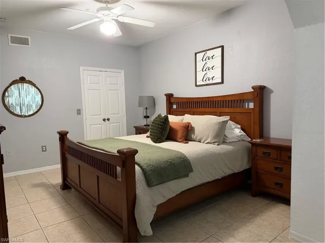 Bedroom featuring ceiling fan, light tile patterned floors, and a closet