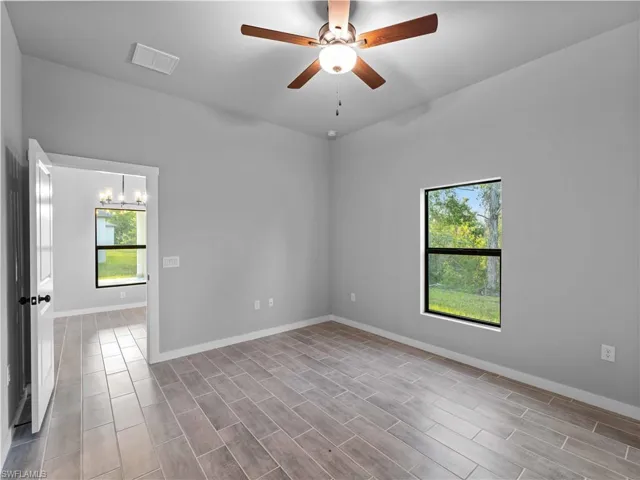 Empty room featuring baseboards, a ceiling fan, and a chandelier