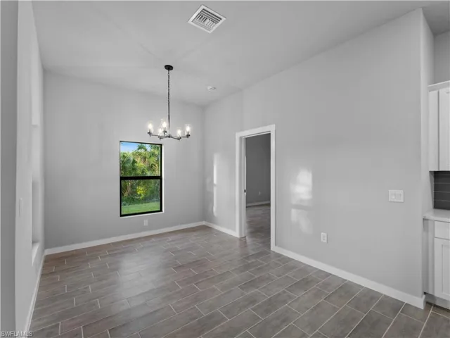 Unfurnished dining area with a chandelier, dark wood-type flooring, and baseboards
