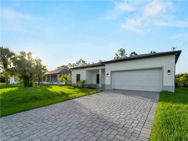 View of front of property with decorative driveway, stucco siding, a garage, and a front yard
