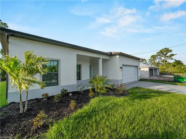 View of front of home featuring stucco siding, a garage, decorative driveway, and a front yard