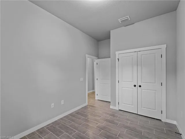 Unfurnished bedroom with baseboards, wood finished floors, a closet, and a textured ceiling