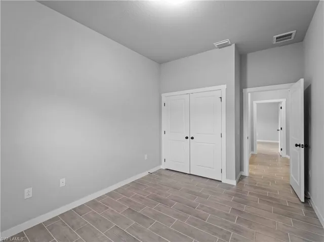 Unfurnished bedroom featuring baseboards, wood tiled floors, and a closet