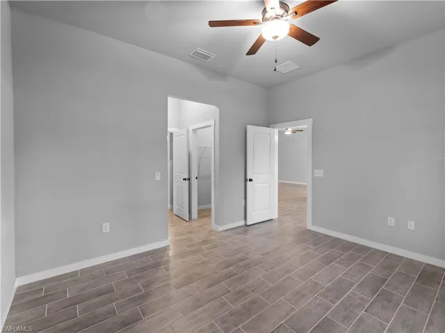 Unfurnished room featuring a ceiling fan, wood finished floors, and baseboards