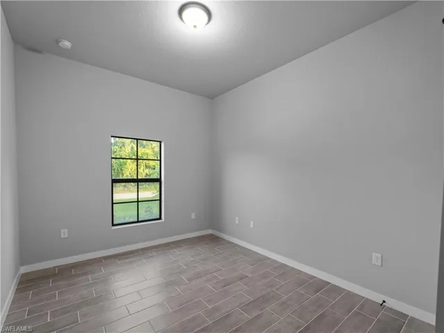 Unfurnished room featuring wood tiled floors and baseboards