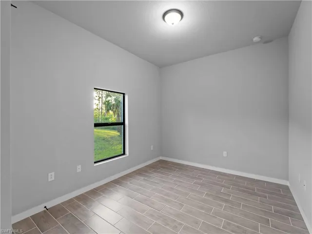 Spare room with wood finish floors, baseboards, and a smoke detector