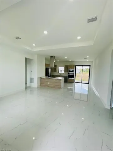 Unfurnished living room with baseboards, marble finish floor, and a tray ceiling